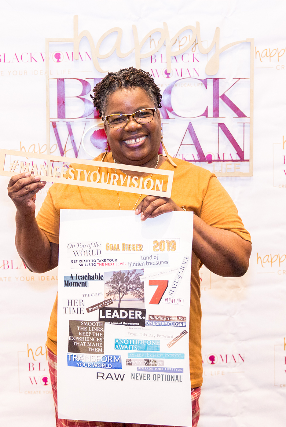 Black woman smiling as she holds up her vision board